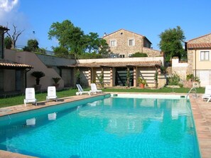 A swimming pool with lounge chairs and a stone building with a tiled roof. - Le Murelle Country Resort (Manciano)