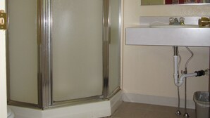Un baño con ducha envuelta en cristal, un lavabo blanco y un espejo sobre él.