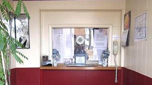 Un área de recepción con un mostrador, un teléfono y un ventanal.