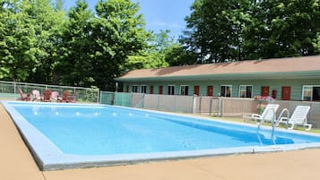 Una piscina al aire libre, sillones reclinables de piscina