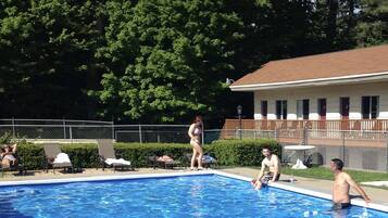 A swimming pool surrounded by trees and a building with a red roof.