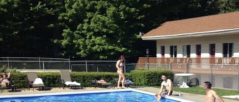 A swimming pool surrounded by trees and a building with a red roof.