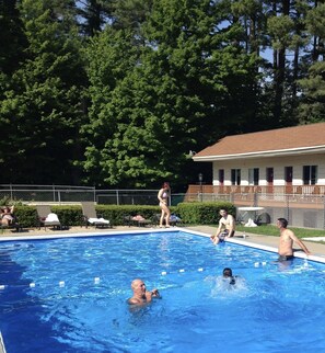 A swimming pool surrounded by trees and a building with a red roof.