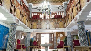A grand hall with ornate columns, a central fountain, and red upholstered chairs. - Moroccan House Hotel Casablanca (Casablanca)
