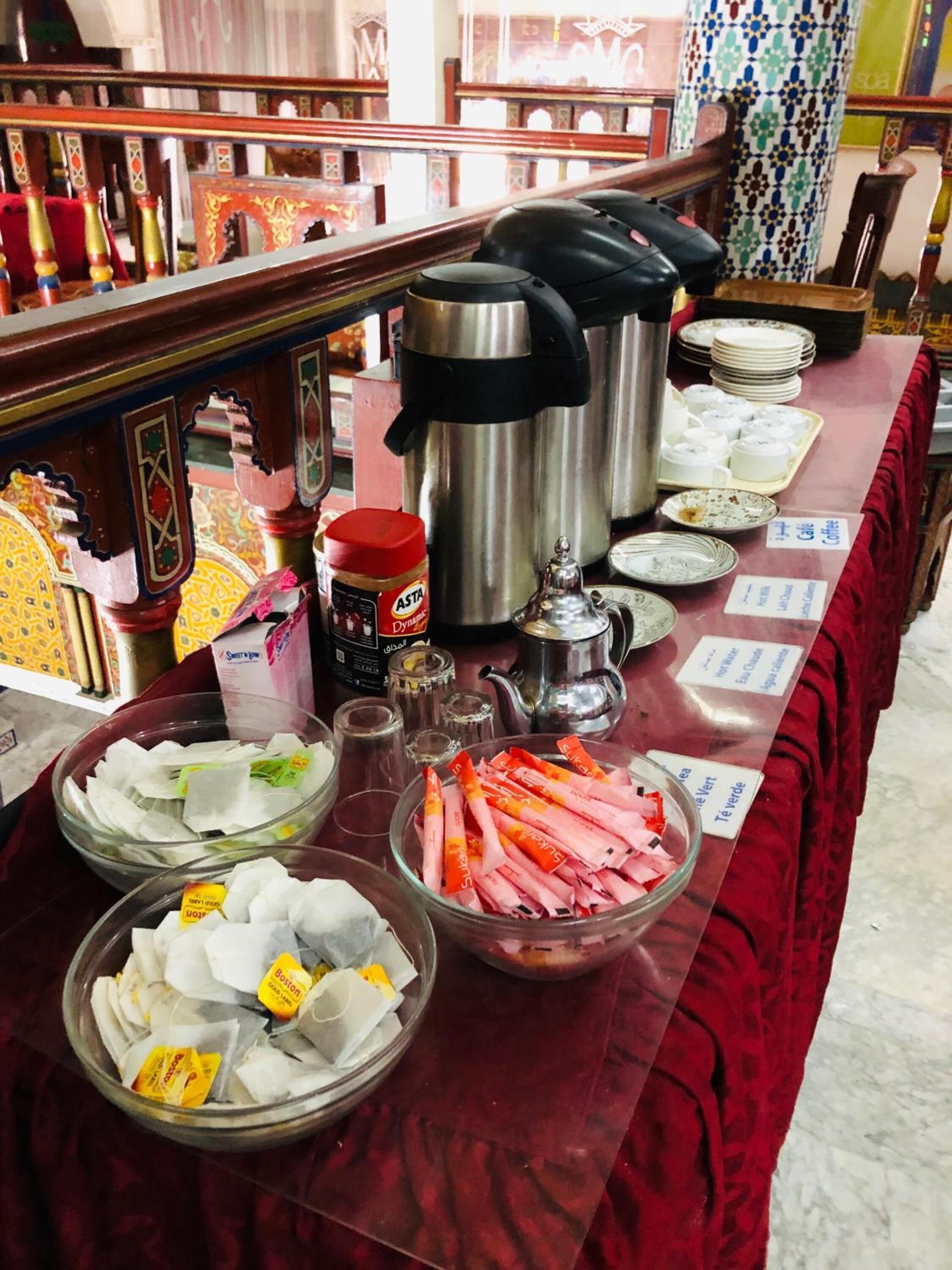 A buffet table with various food items and condiments, including bowls of snacks, a coffee station, and a jar of sauce.