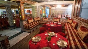 A traditional interior with patterned walls, a central dining area with red tablecloths, and ornate seating. - Moroccan House Hotel Casablanca (Casablanca)