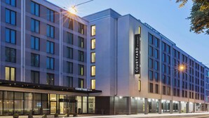 A modern hotel with a prominent 'Courtyard by Marriott' sign, large windows, and a well-lit entrance area. - Courtyard München City Ost (Munich)