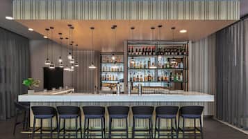 A modern bar area with a long counter, multiple hanging pendant lights, and a variety of bottles and glasses on shelves.