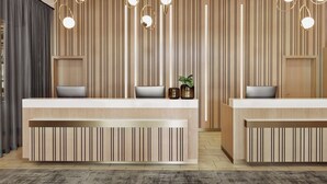 A modern reception area with two reception desks, vertical wooden paneling, and pendant lighting. - Courtyard München City Ost (Munich)