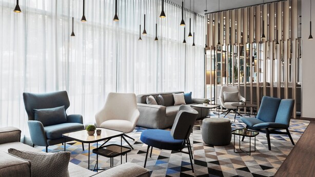 A modern lounge area with sofas, armchairs, and a coffee table. - Courtyard München City Ost (Munich)