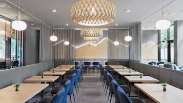 Un comedor moderno con mesas largas, sillas azules y una gran lámpara decorativa.