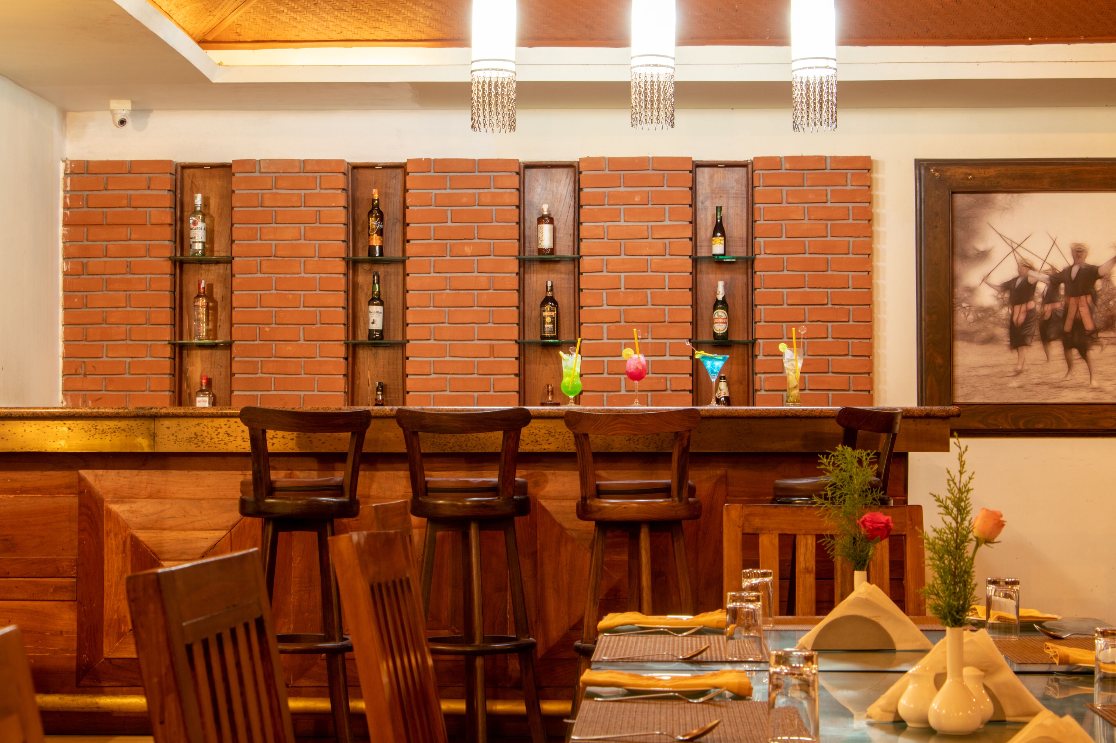 Ein Restaurant mit Backsteinwänden, Holzbänken und einer Bar mit Flaschen und Gläsern.