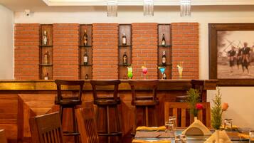 Ein Restaurant mit Backsteinwänden, Holzbänken und einer Bar mit Flaschen und Gläsern.