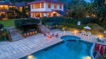 A two-story house with a swimming pool, outdoor seating, and a well-maintained garden.