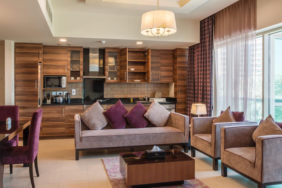 Un salon moderne comprenant un canapé, deux fauteuils, une table basse et un coin repas avec une table et des chaises.