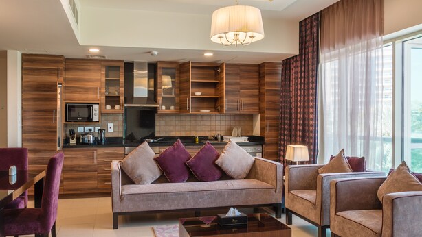 Een moderne woonkamer met een bank, twee fauteuils, een salontafel en een eethoek met een tafel en stoelen.