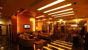 Een moderne lobby met een receptiebalie, een zithoek en een glazen lift.