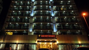 Een hotel met meerdere verdiepingen, modern van ontwerp, met een opvallende ingang en een bord waarop staat dat het Dunes Hotel Apartments is.
