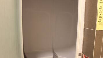 Features a white shower enclosure and plain walls with decorative tiles.
