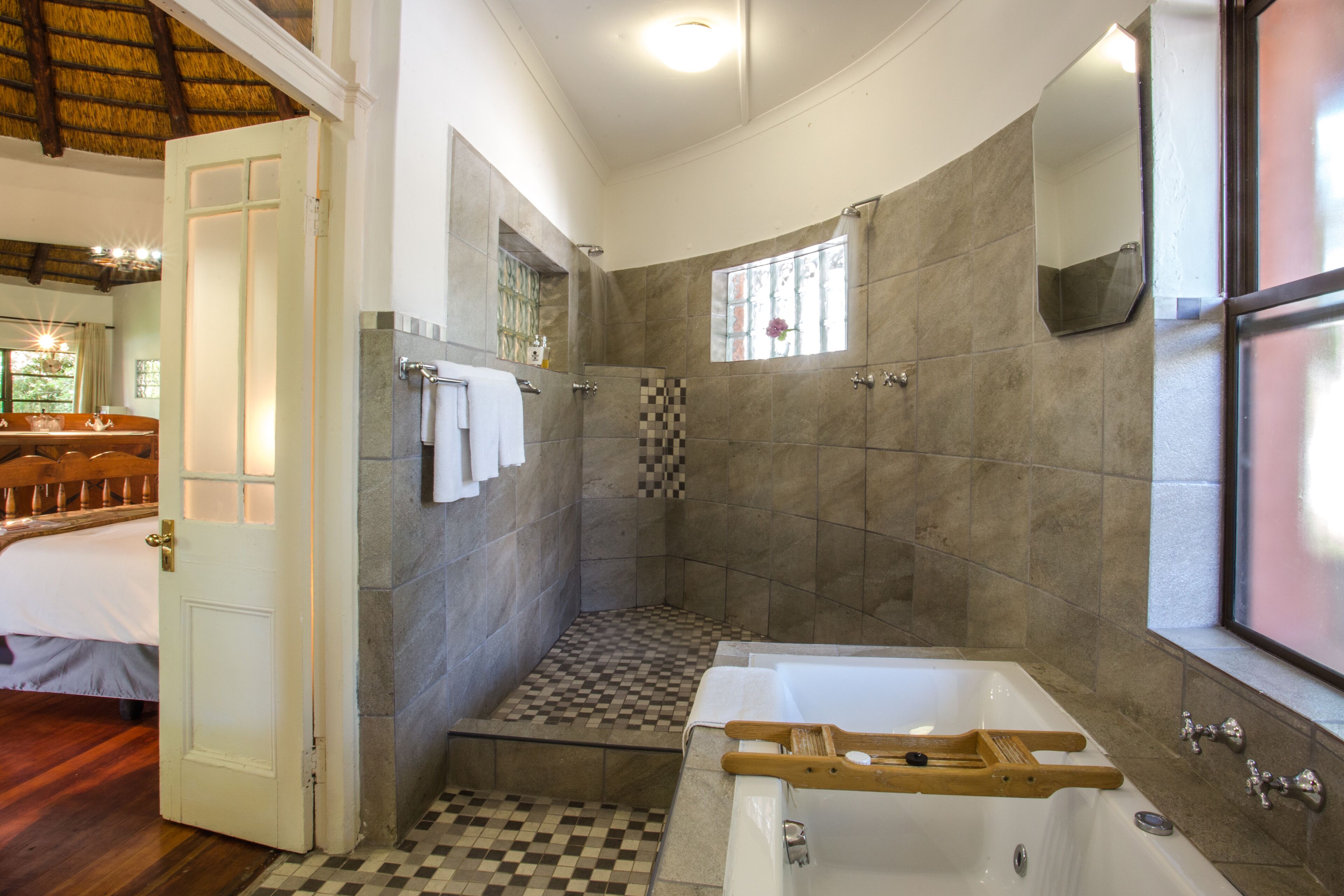 Un baño con piso a cuadros, una bañera, una ducha y una ventana con vistas.