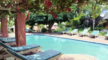 A pool area with lounge chairs and a pergola covered with climbing plants.