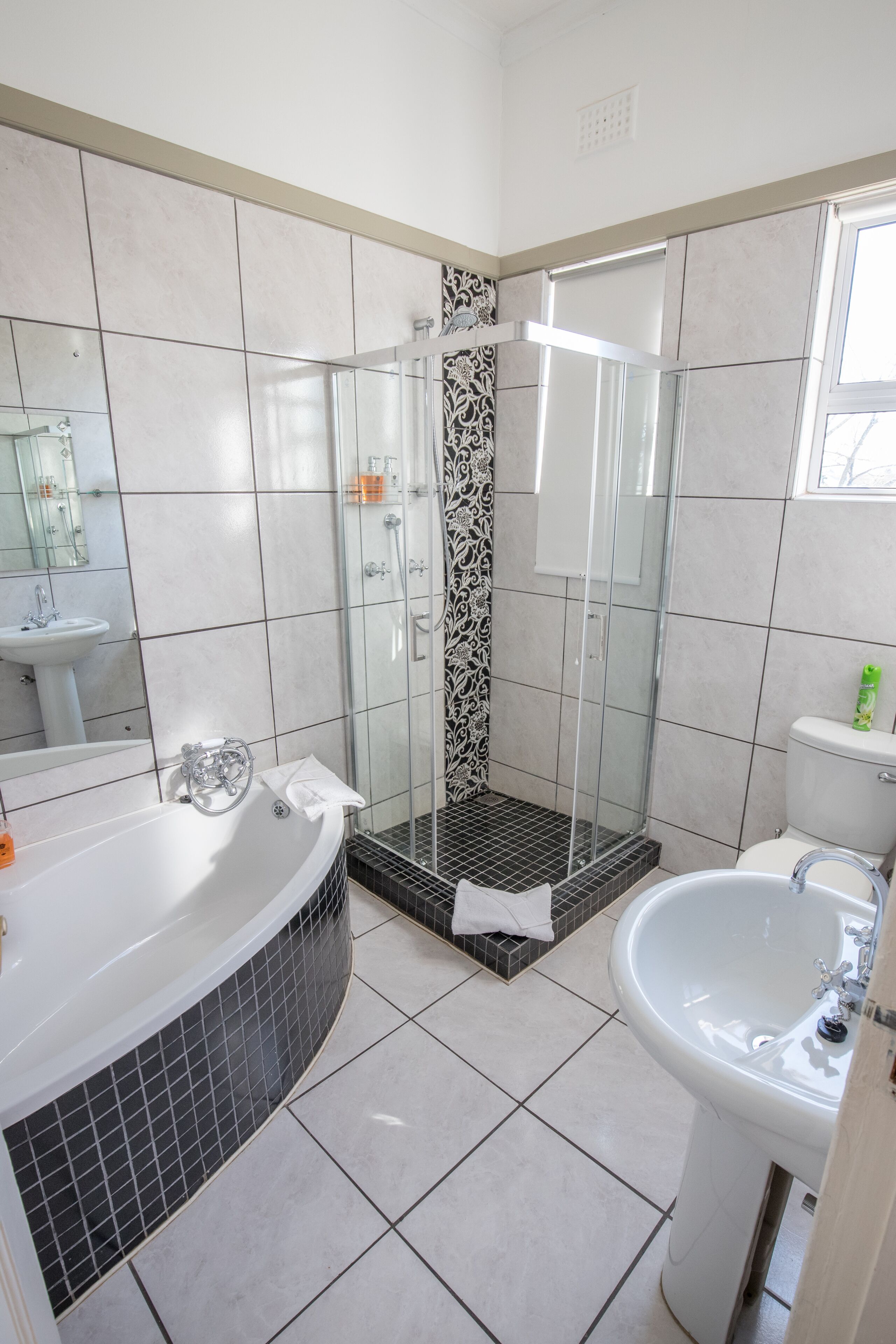 A modern bathroom with a glass-enclosed shower, a freestanding bathtub, and a pedestal sink.