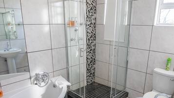 A modern bathroom with a glass-enclosed shower, a freestanding bathtub, and a pedestal sink.