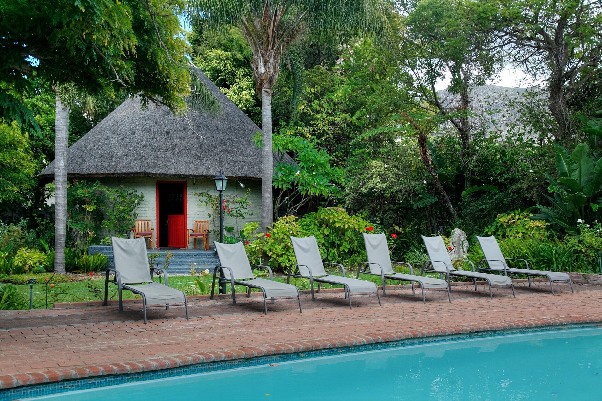 A poolside area with lounge chairs and a thatched-roof building.