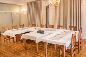 A dining area with a long table set for six, wooden chairs, and a chandelier.
