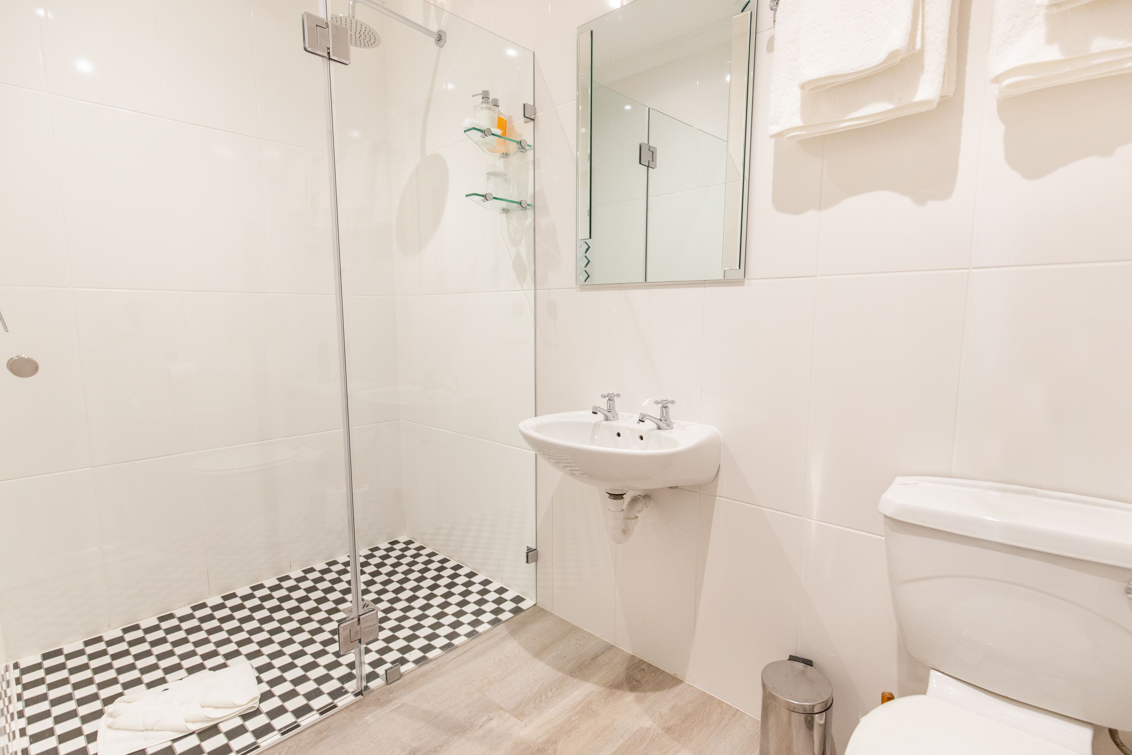A modern bathroom with a glass shower enclosure, a white sink, and a toilet.