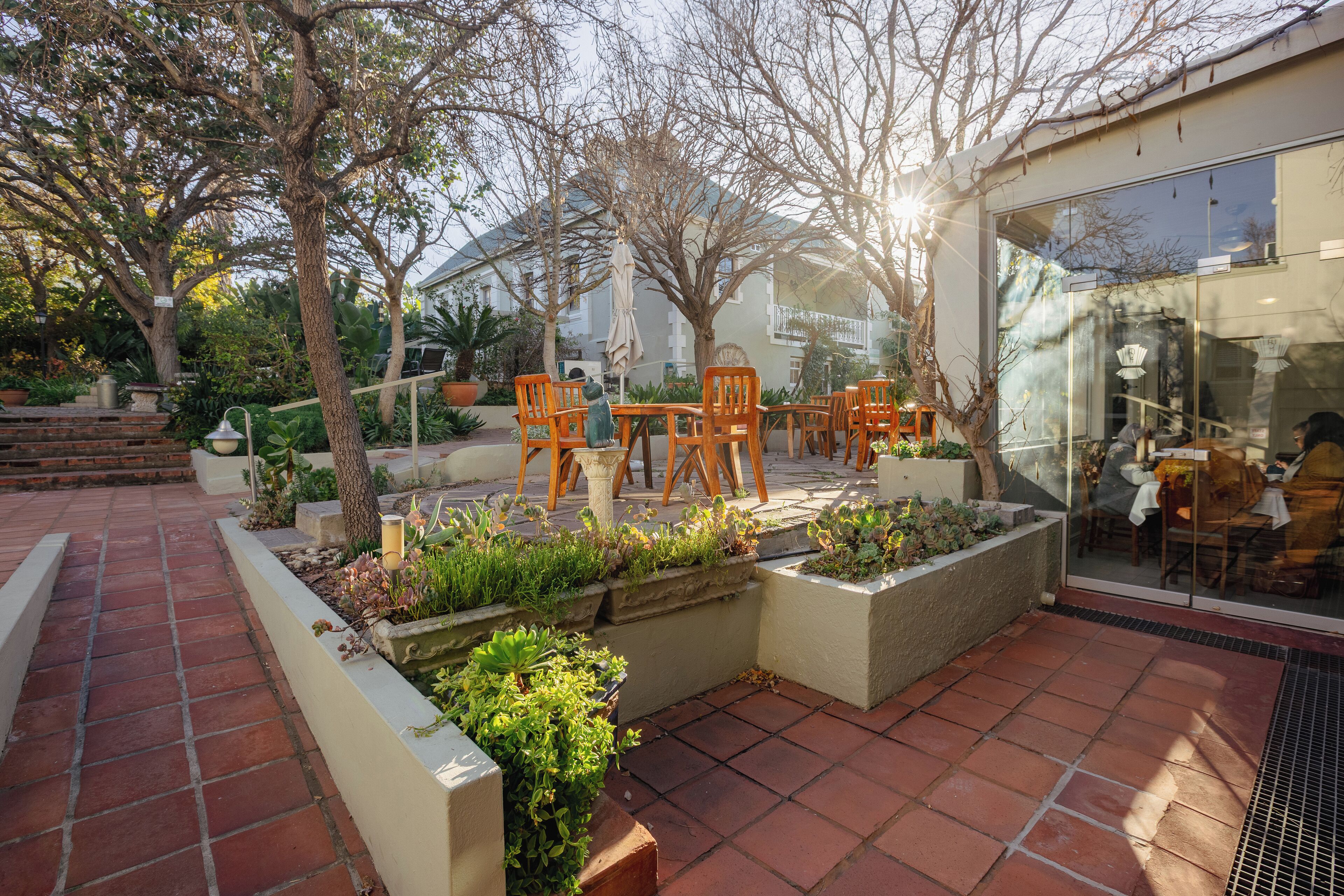 A patio area with outdoor seating, planters with greenery, and a building with large windows.