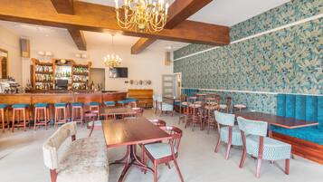 A restaurant with wooden beams, a bar area with stools, and patterned wallpaper.