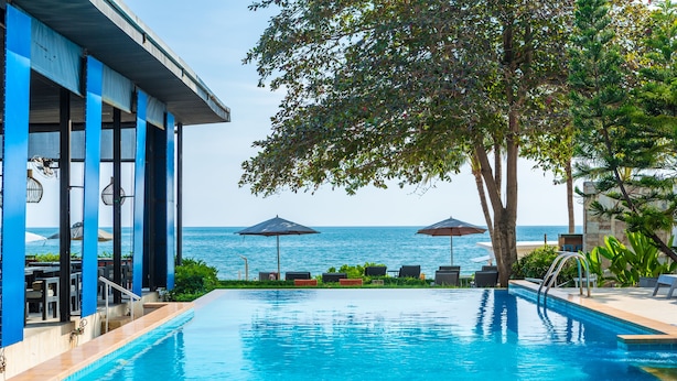 Piscina con vista al mar, sillas de descanso y sombrillas.