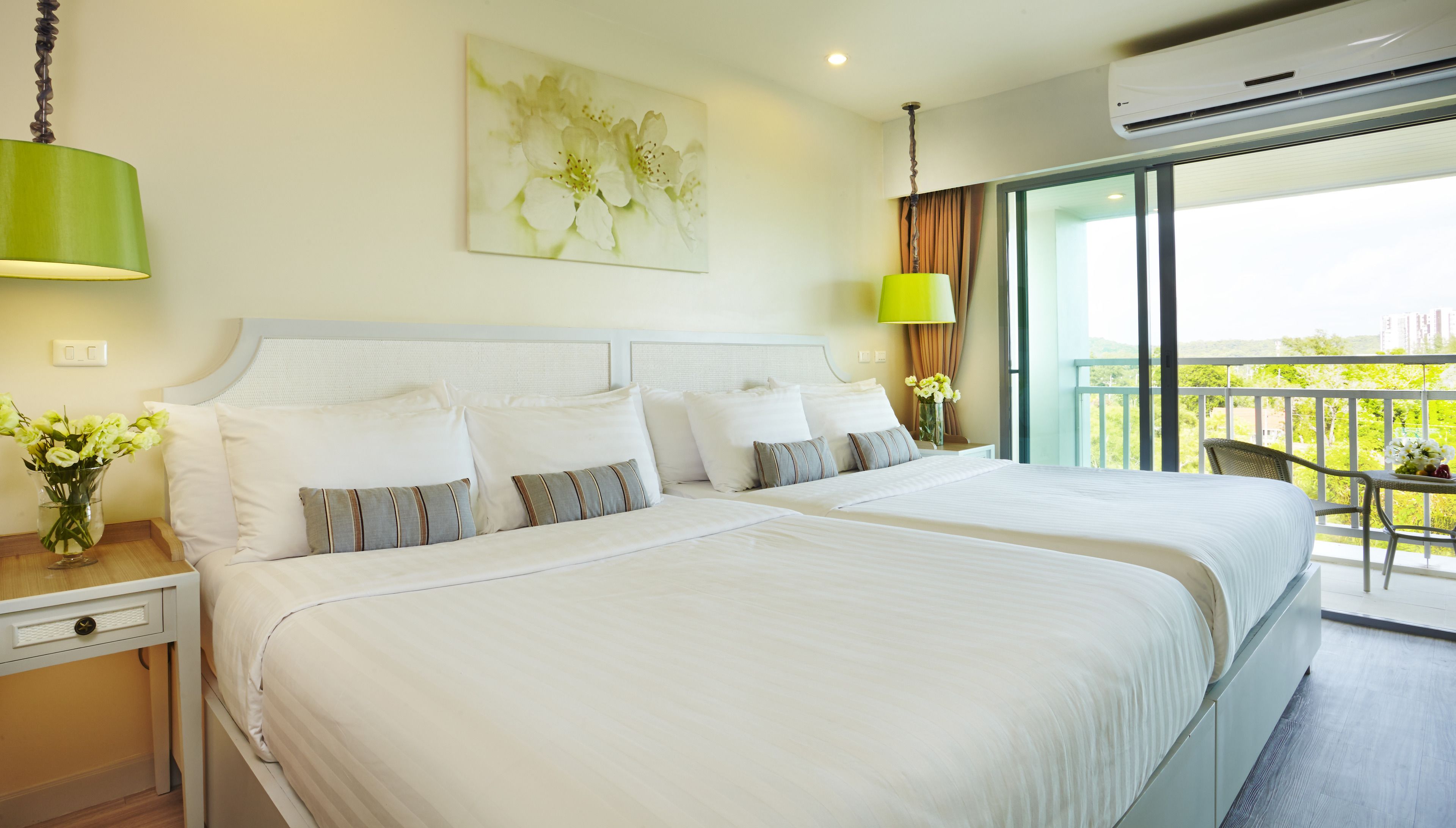 Habitación de hotel con dos camas, un ventanal grande y balcón con vistas.