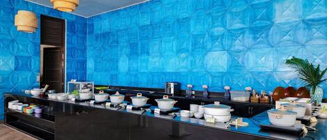 Una cocina moderna con un salpicadero azul con diseño, encimeras negras y varios electrodomésticos.