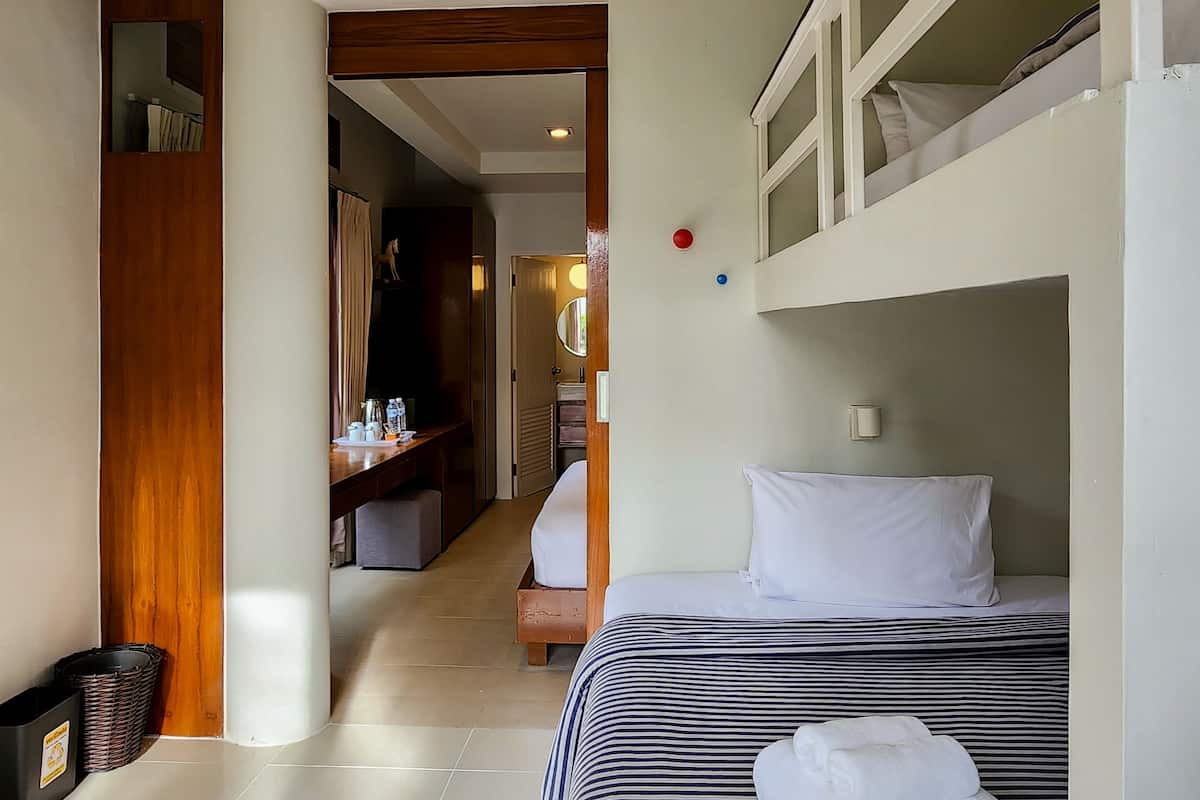 A hotel room with a bunk bed, a desk, and a bathroom visible through an open door.
