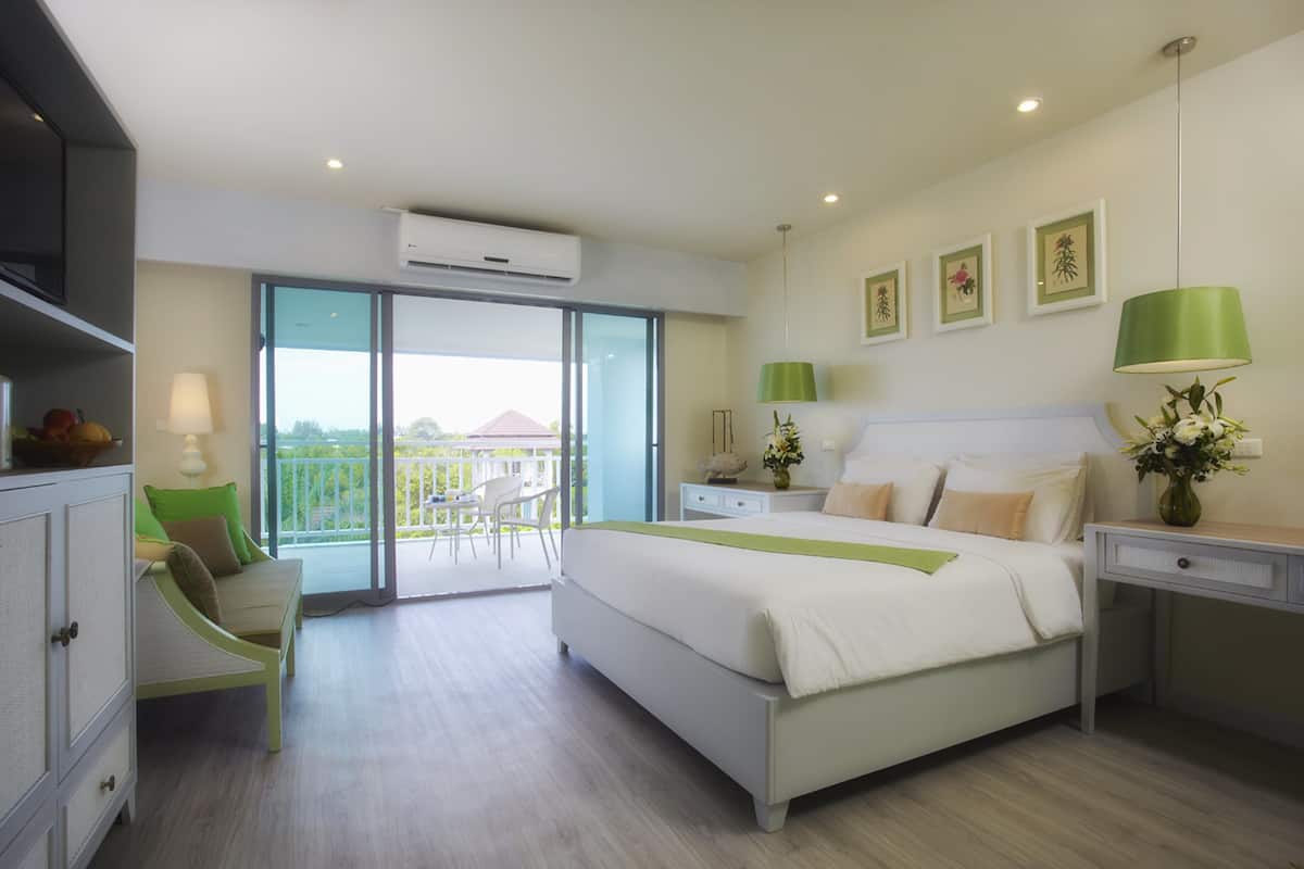 A modern bedroom with a large bed, a desk, a chair, and a balcony with a view.