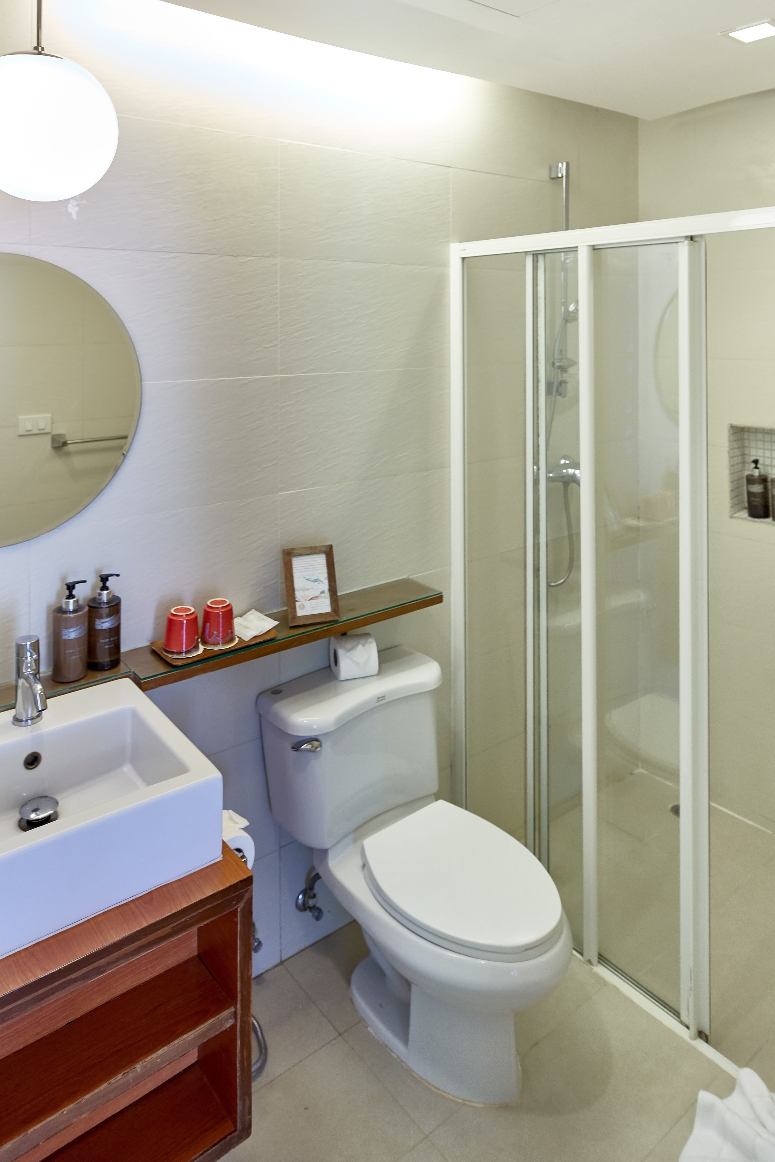 A bathroom with a white sink, toilet, and glass-enclosed shower.
