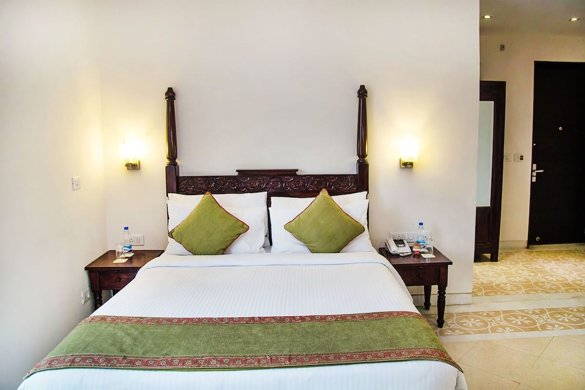 A hotel room with a large bed, two bedside tables, and a door leading to another room.