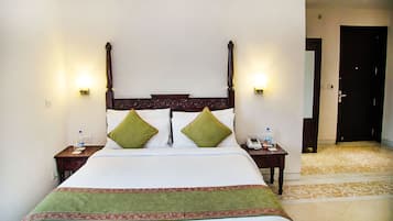A hotel room with a large bed, two bedside tables, and a door leading to another room.