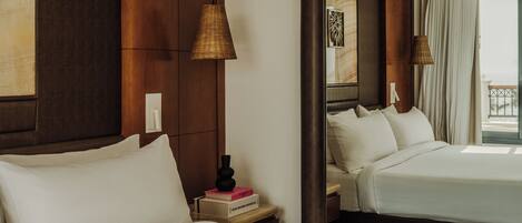 Habitación de hotel con dos camas, una mesita de noche con lámpara, un espejo y vistas al exterior.