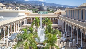 A courtyard with a central fountain, surrounded by palm trees and outdoor seating. - RedLevel at Gran Melia Palacio de Isora - Adults Only (Guia de Isora)
