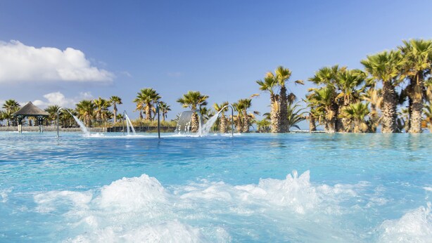 A pool with clear blue water, surrounded by palm trees and a gazebo. - RedLevel at Gran Melia Palacio de Isora - Adults Only (Guia de Isora)