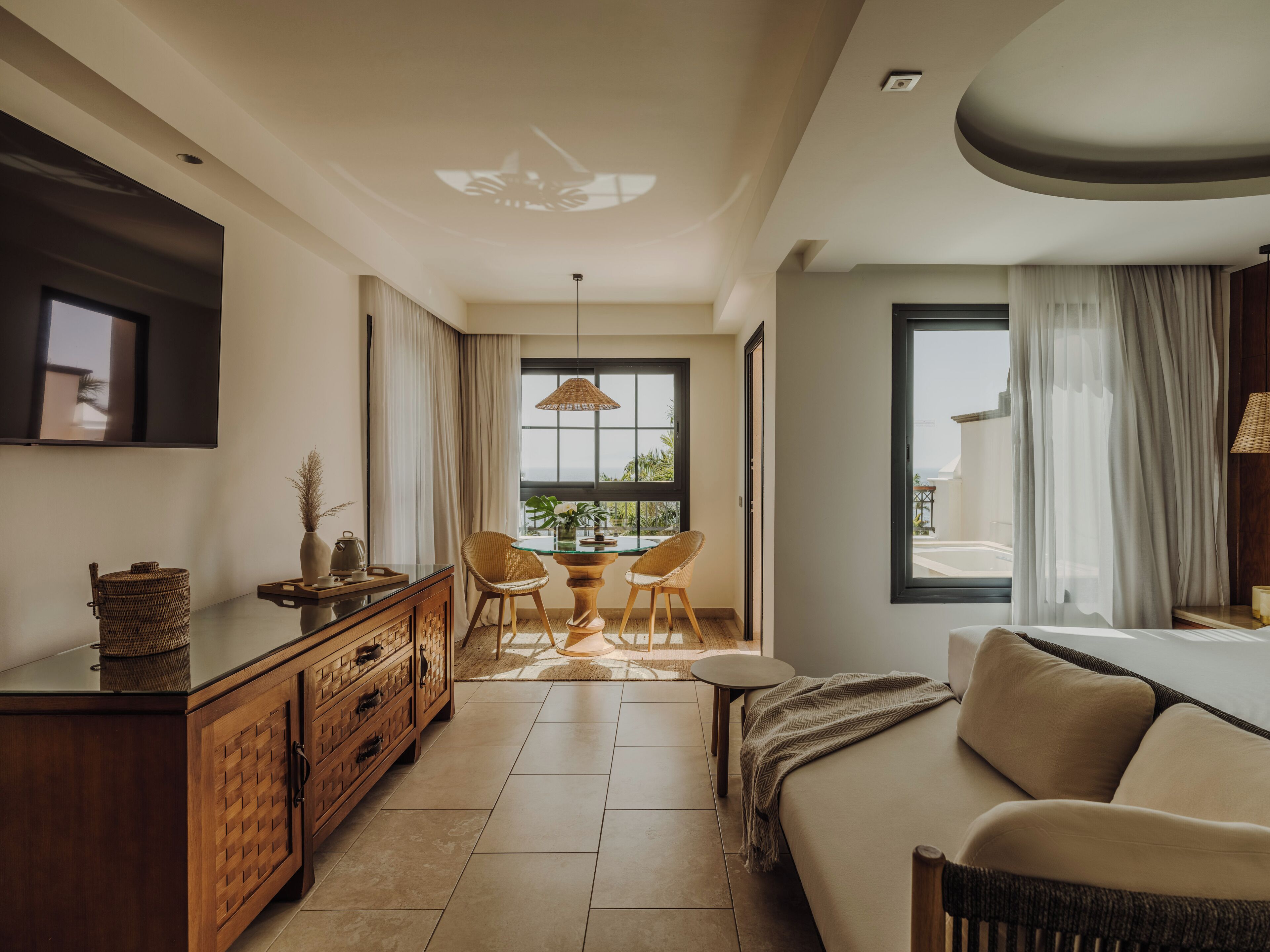 Una sala moderna con un sofá, una mesa de comedor y un televisor. Se ve el exterior a través de una ventana.