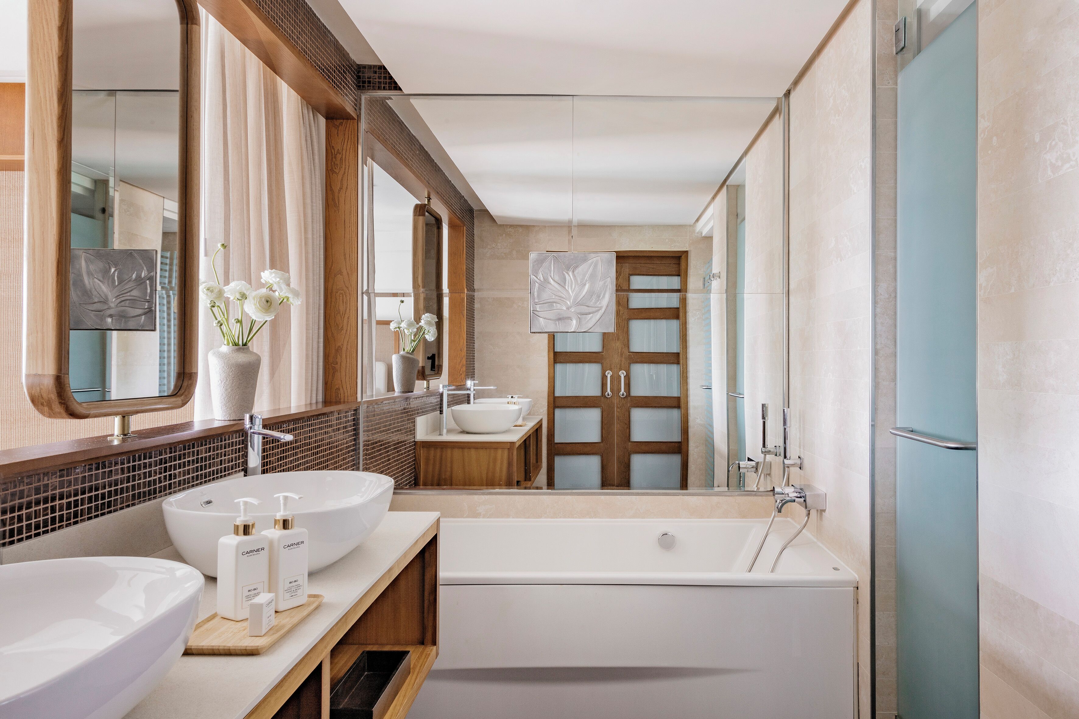 Ein modernes Badezimmer mit einer großzügigen Badewanne, zwei Waschbecken und einem Spiegel.