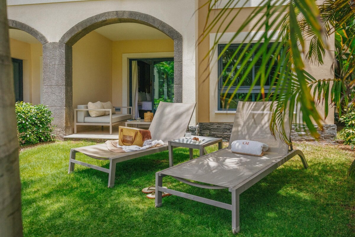 Un espace extérieur ensoleillé, aménagé avec deux fauteuils de relaxation, une table et un petit canapé.