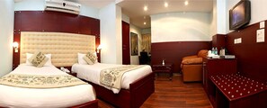 A hotel room with two beds, a TV, a desk, and a seating area.
