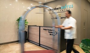 Entrada de un hotel con un cartel que dice 'Fahrenheit Suites Kuala Lumpur' y una señalización que indica 'Berjaya Vacation City Residences, 5to piso'.