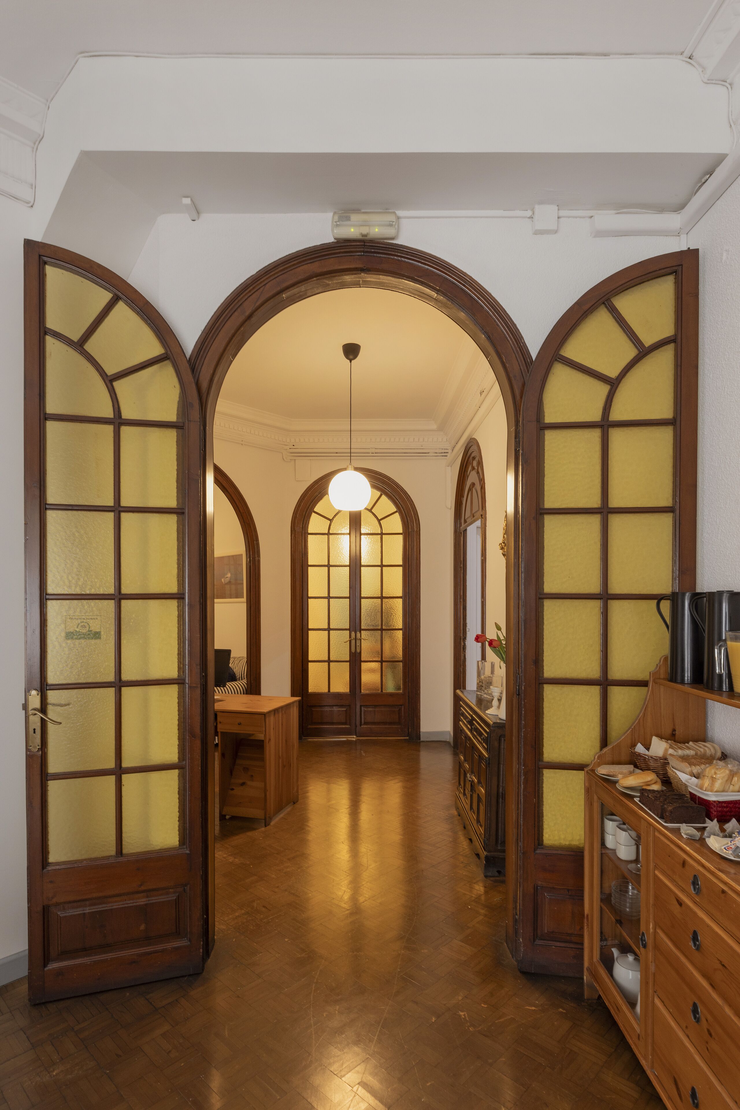Un pasillo con puertas de madera y un candelabro.