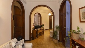 Un couloir avec des portes en bois, un bureau avec un ordinateur et des plantes en pot.